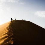 five people standing on sand dunes during daytime