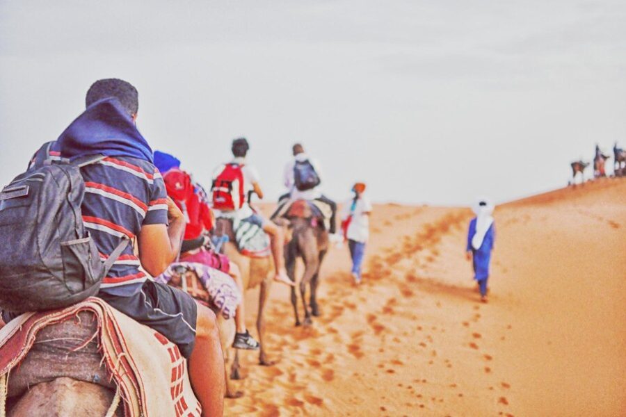 rear-view-people-riding-camels-desert_1048944-5866467